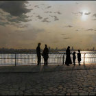 Silhouetted figures on waterfront walkway at golden sunset