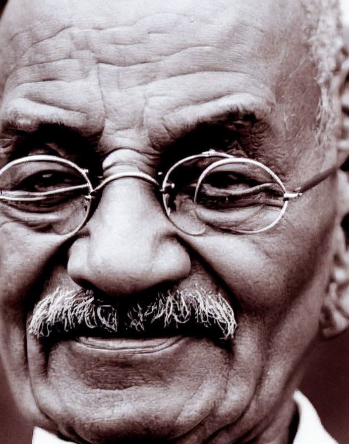 Elderly man with mustache and round glasses smiling