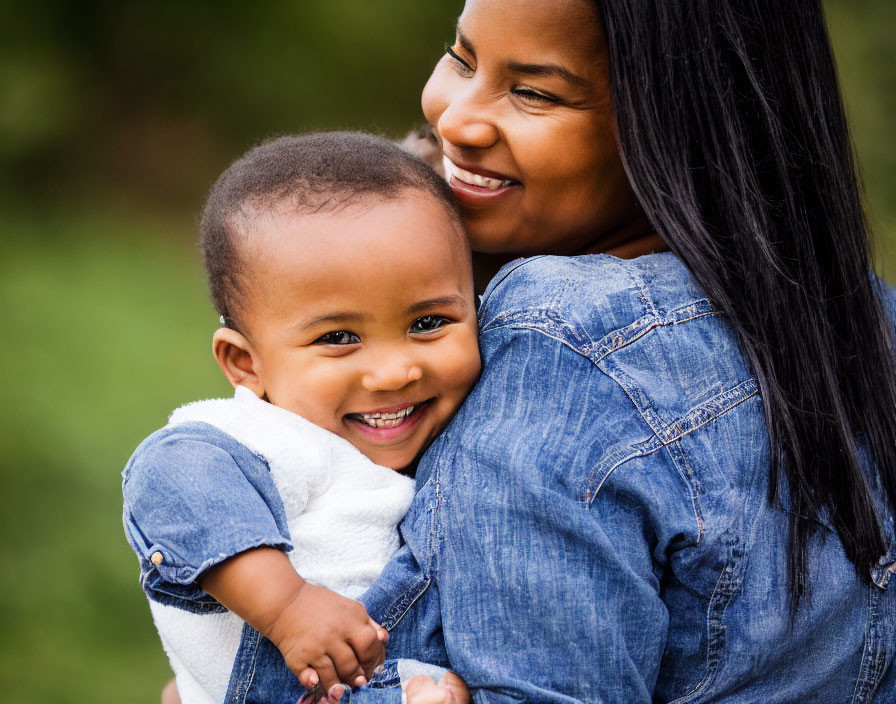 Smiling woman in denim embraces happy toddler outdoors