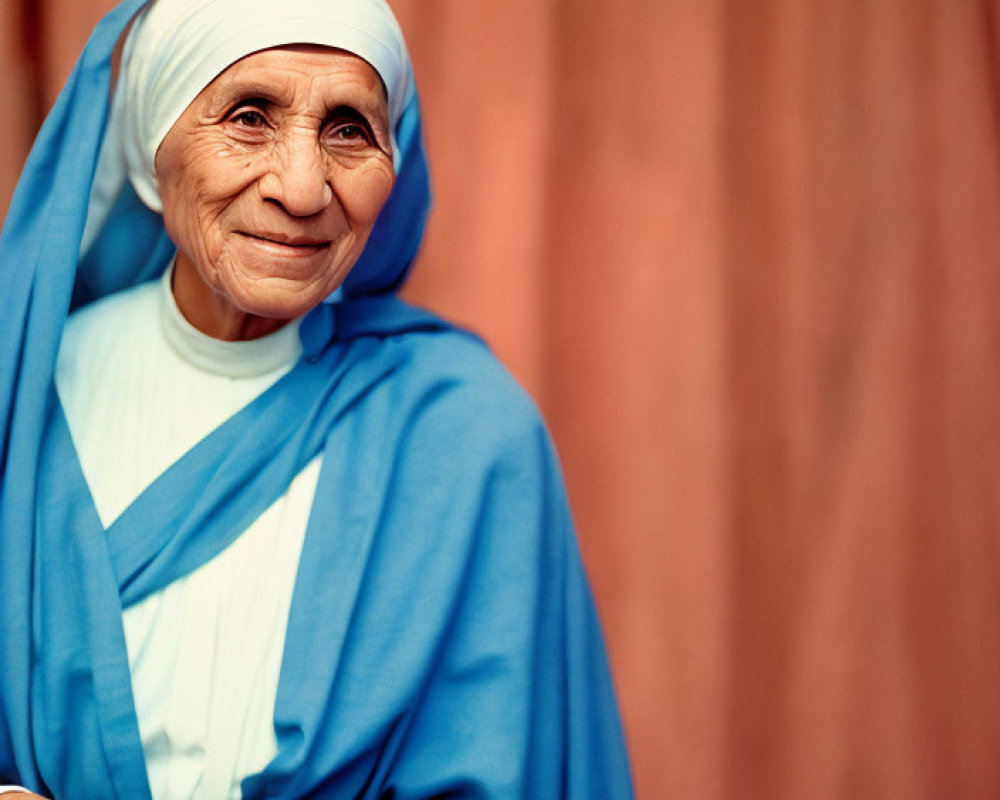 Elderly woman in white headdress and blue robe smiling