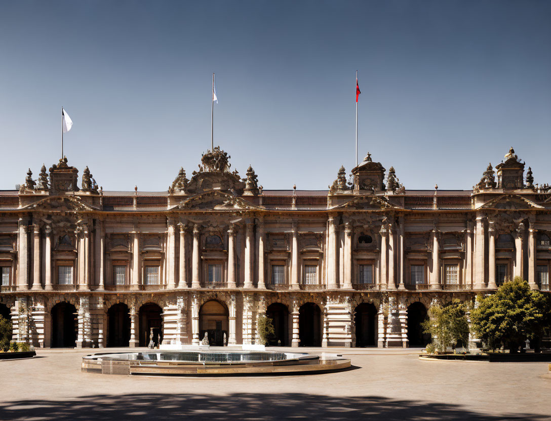 Historic building with intricate facades and flags, courtyard fountain under clear sky