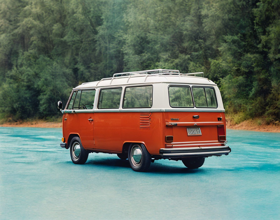 Red Volkswagen bus parked on glossy surface with lush green forest background