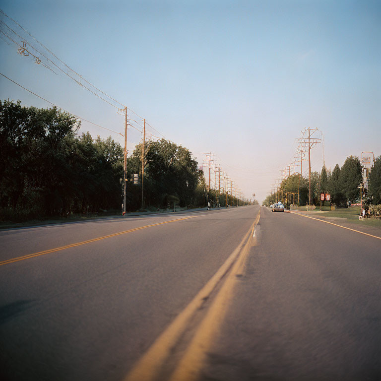 Tranquil Dusk Scene: Yellow Lane Markings, Power Lines, Greenery