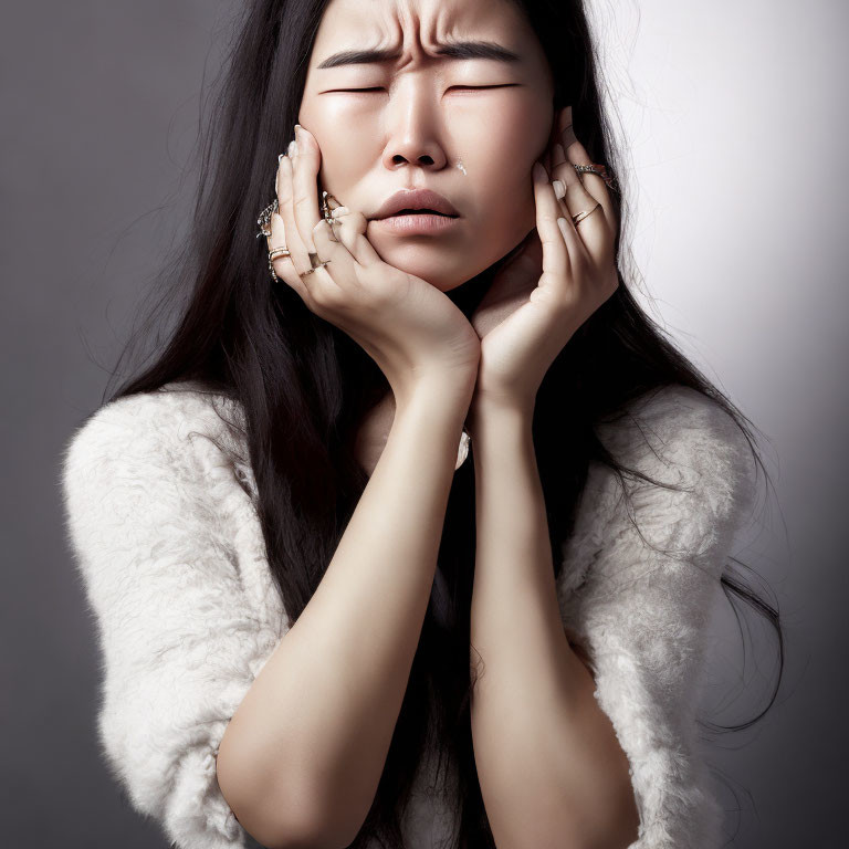 Woman in white furry outfit distressed, holding face in discomfort.