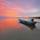 Boats on mirror-like water under ornate, glowing sky