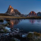 Vibrant flora, luminescent buildings, reflective lake in a nocturnal landscape