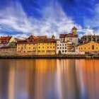 Panoramic fantasy landscape with ornate buildings, reflecting water, fluffy clouds, flying bird