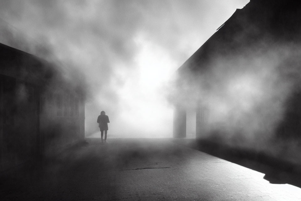 Misty alleyway scene with solitary figure and piercing light