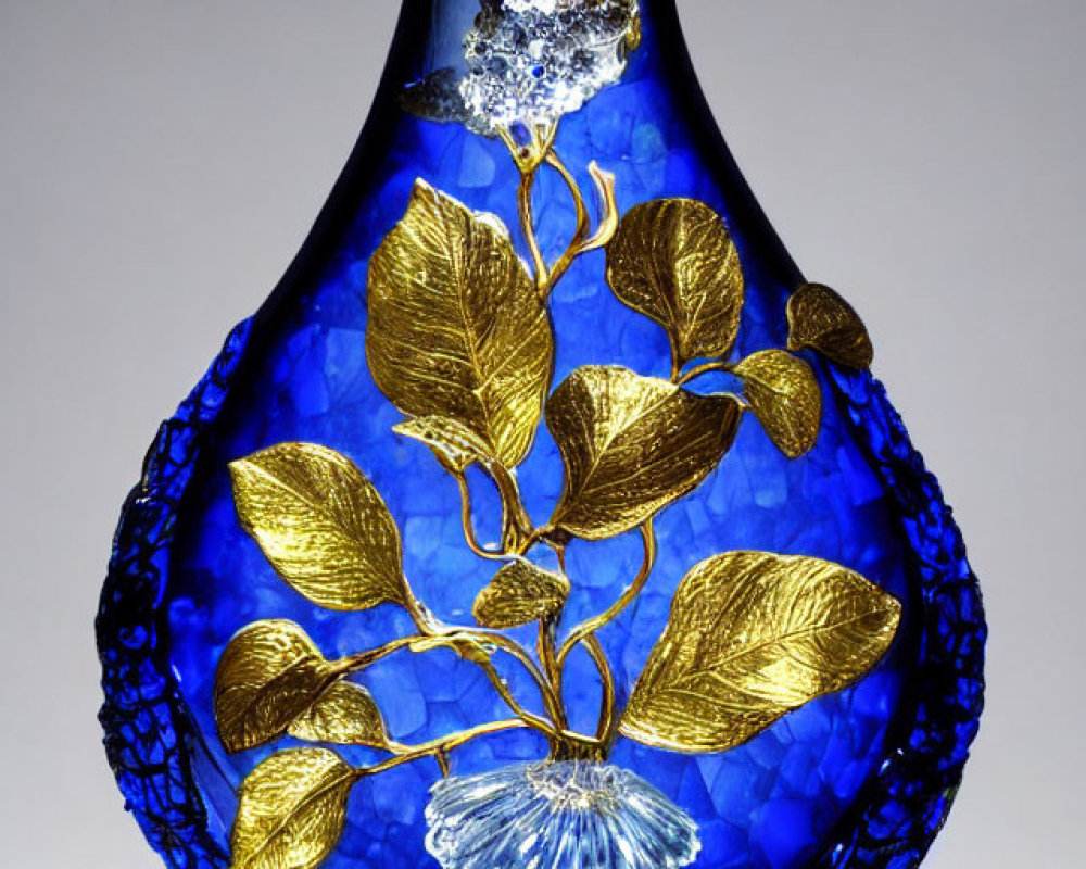 Blue Glass Vase with Gold Leaf Accents and Floral Design on Light Surface