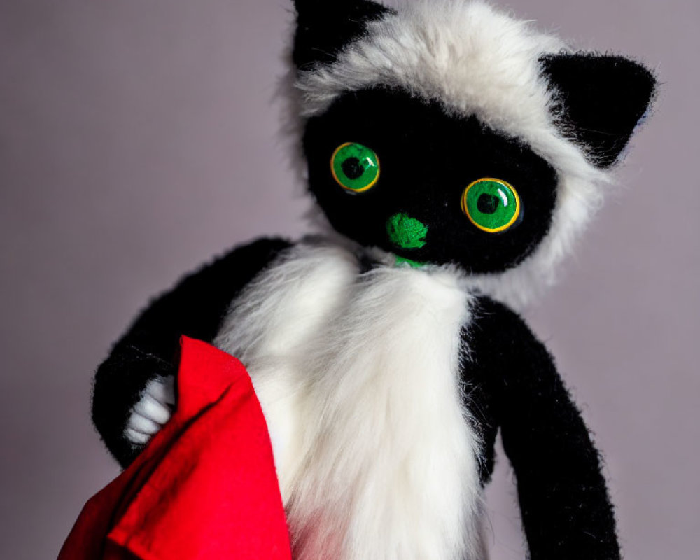 Black and White Cat Plush Toy with Green Eyes and Red Cape on Purple Background