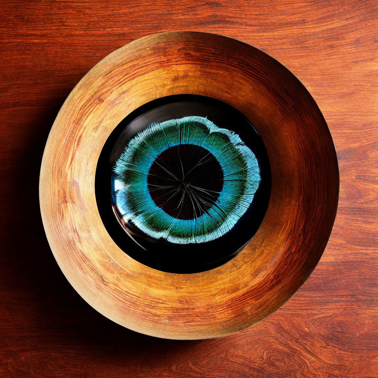 Wooden Bowl with Detailed Blue and Green Eye Design on Wood Grain Surface