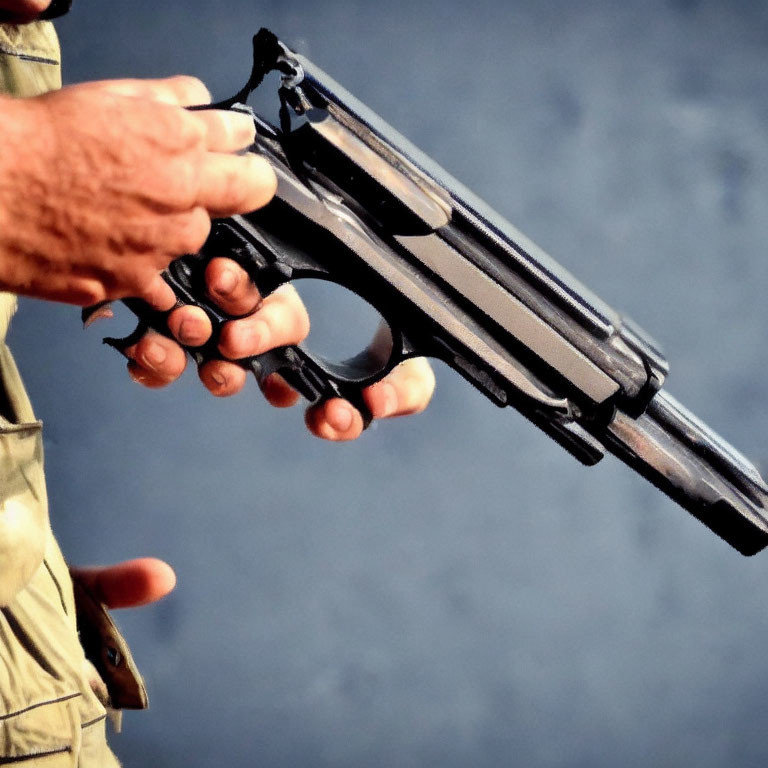 Detailed close-up of hand holding black handgun with fingers on trigger guard