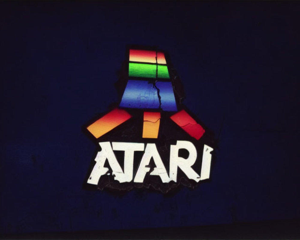 Colorful Illuminated Atari Logo on Dark Blue Background with Torn Surface