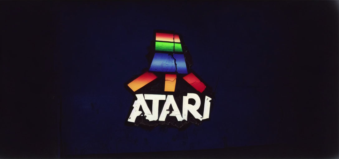 Colorful Illuminated Atari Logo on Dark Blue Background with Torn Surface