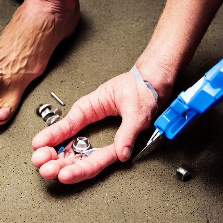 Person injecting hand with blue syringe among scattered mechanical parts