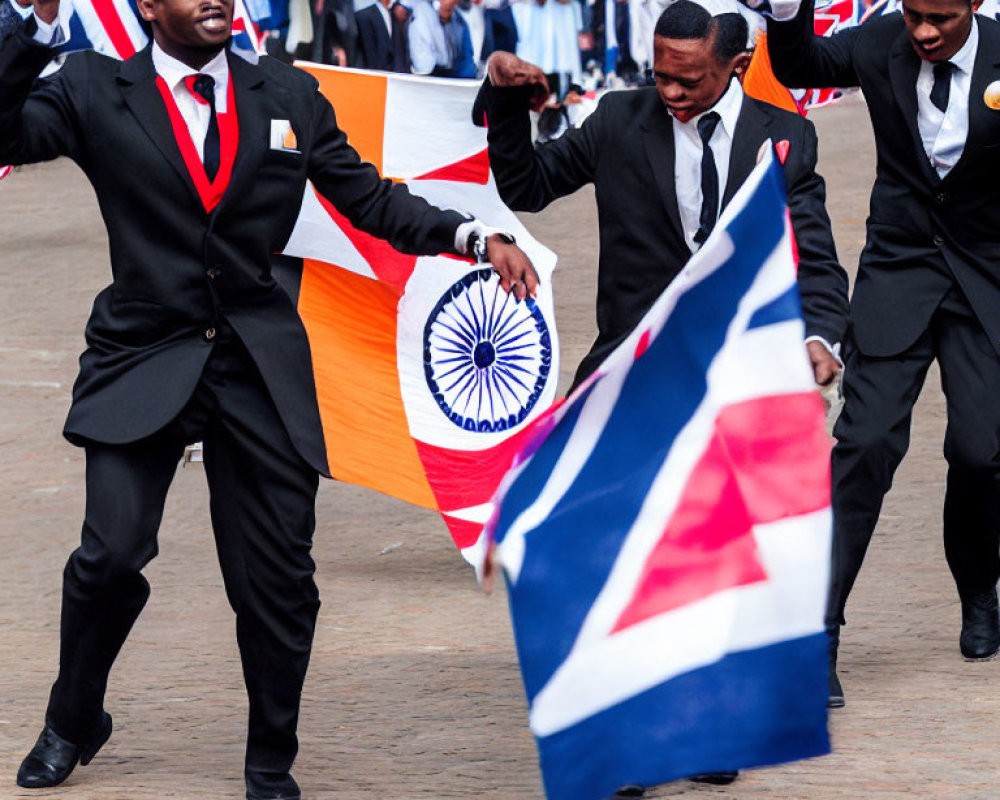 Men in suits waving Indian and British flags at outdoor event