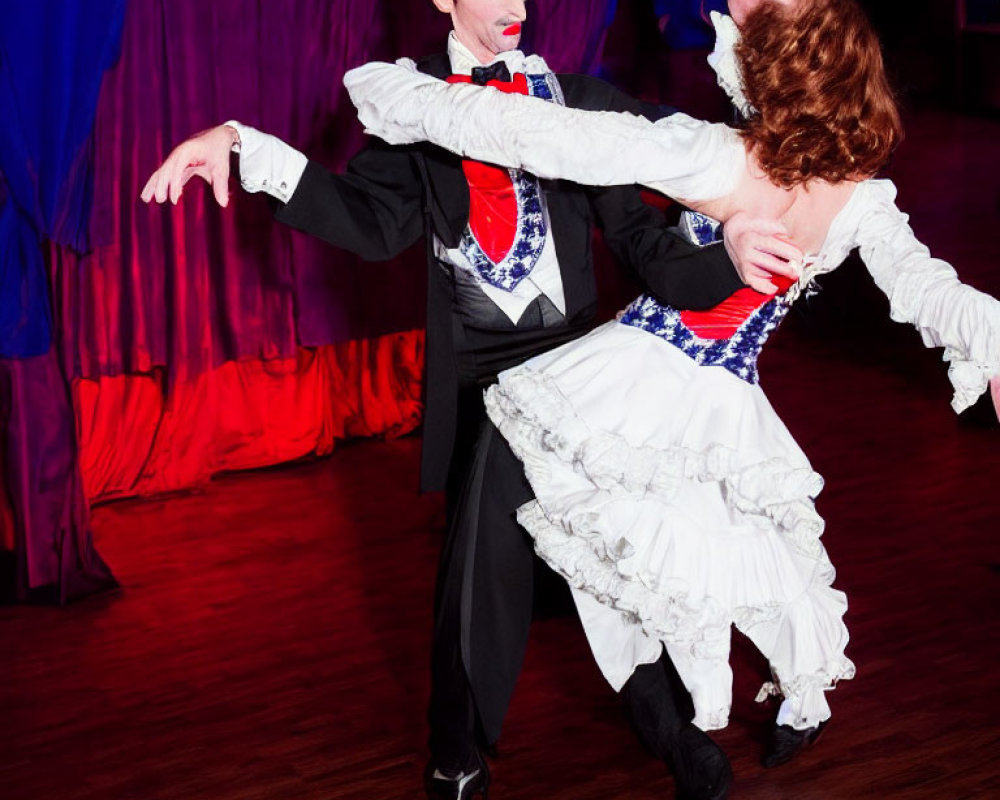 Elaborately costumed dancers perform dramatic dip on stage