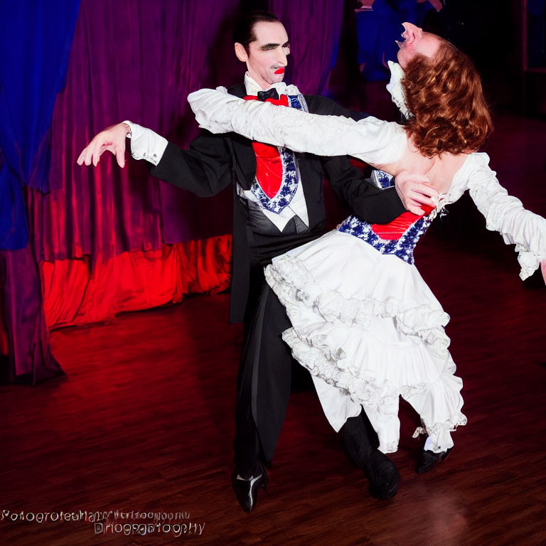 Elaborately costumed dancers perform dramatic dip on stage