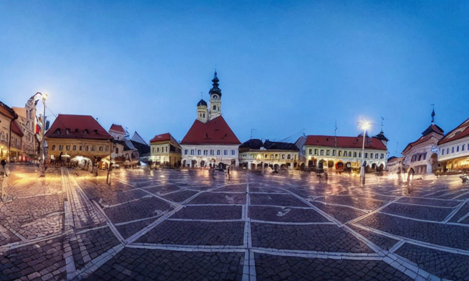 Traditional town square with cobblestones, buildings, and clock tower at dusk