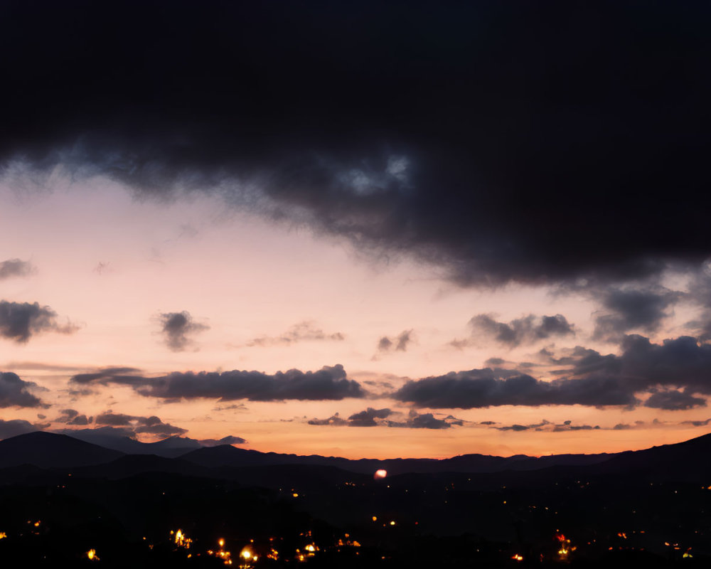 Scenic sunset panorama with silhouetted mountains and town lights