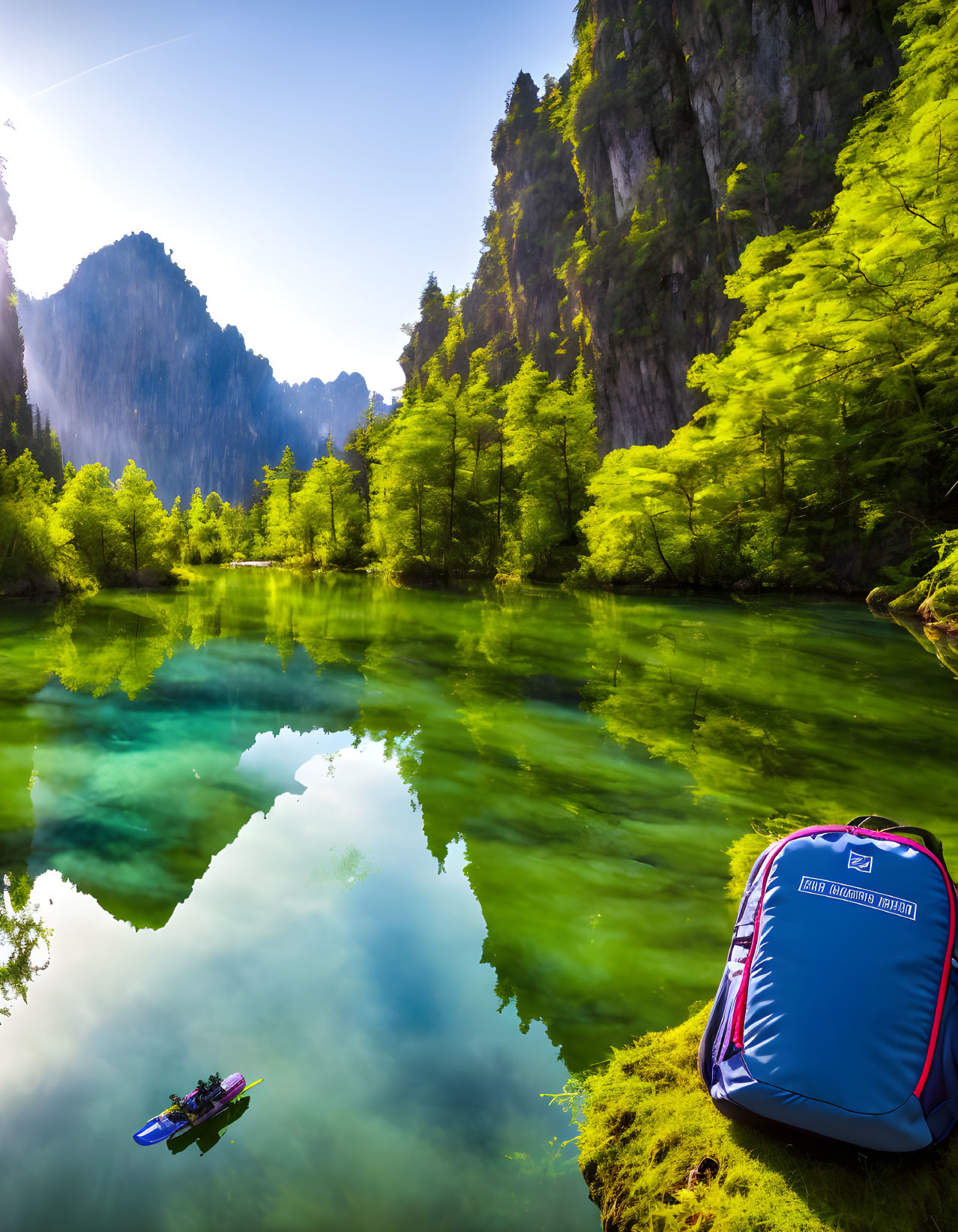 Tranquil lake scene with towering cliffs, lush greenery, kayak, and backpack