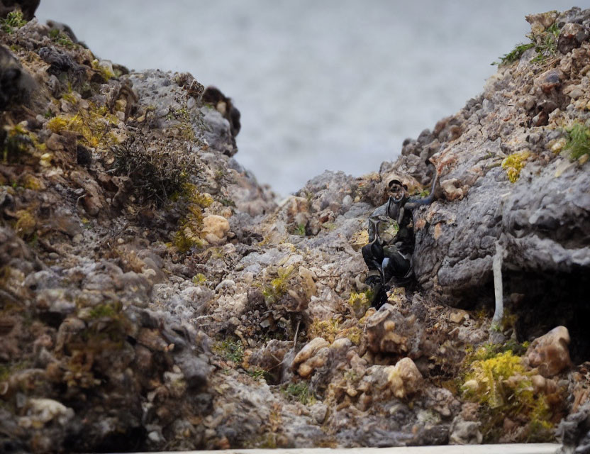 Miniature hiker figure in rocky terrain with river backdrop