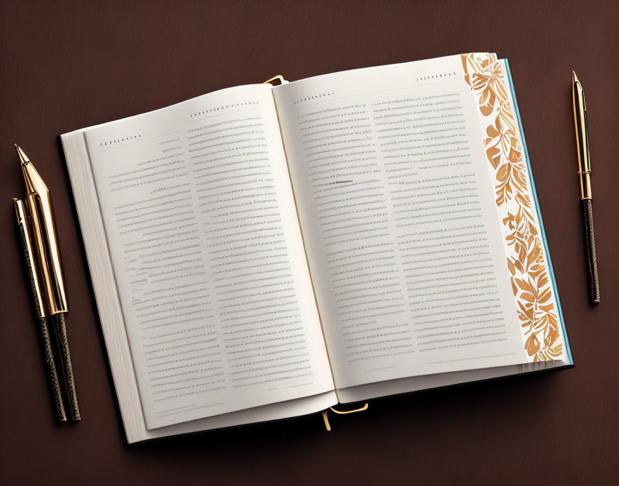 Open book with floral patterns and pens on brown background