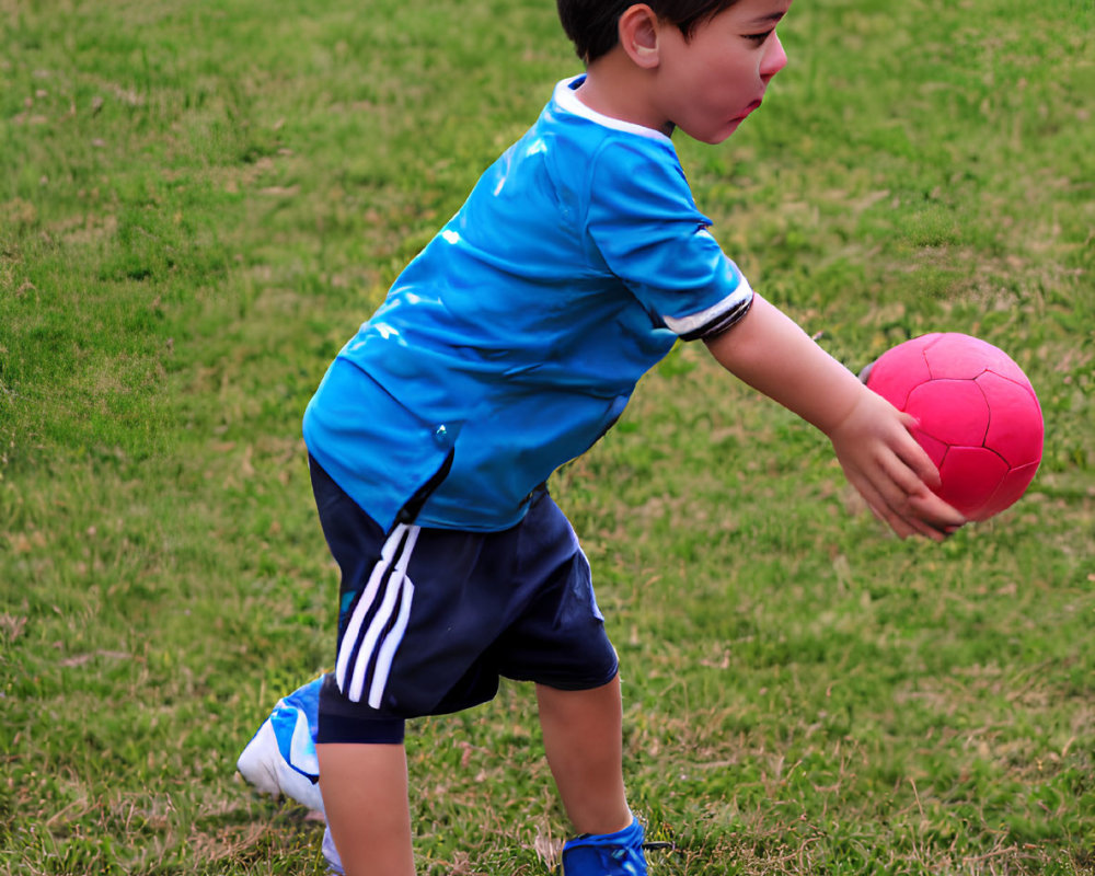 Child in Blue Shirt Playing with Pink Ball on Grass Field