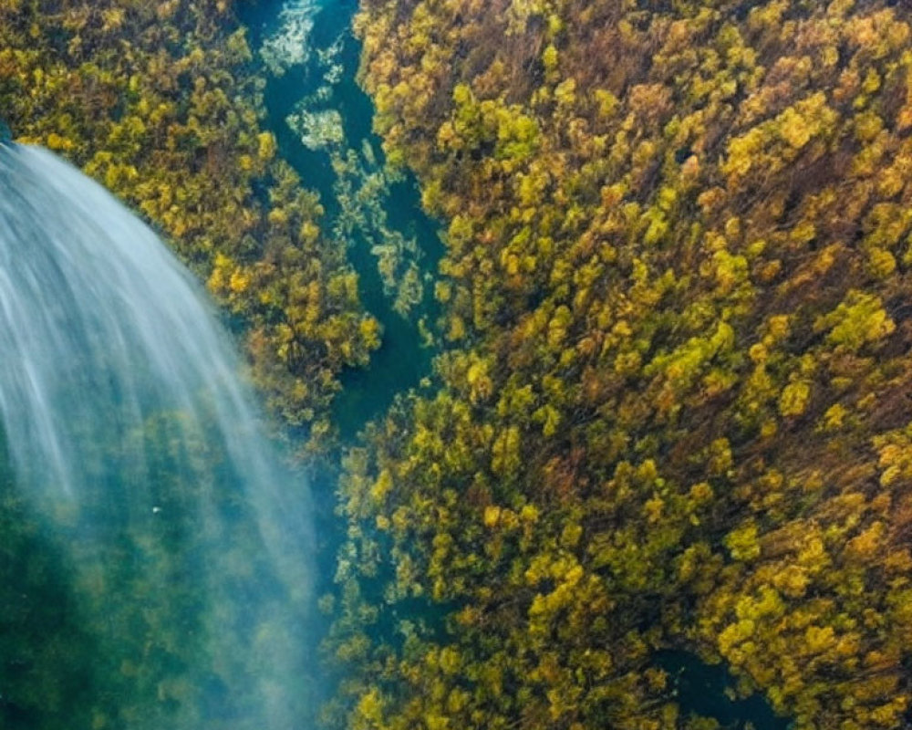 Scenic aerial view of misty waterfall in orange and green forest