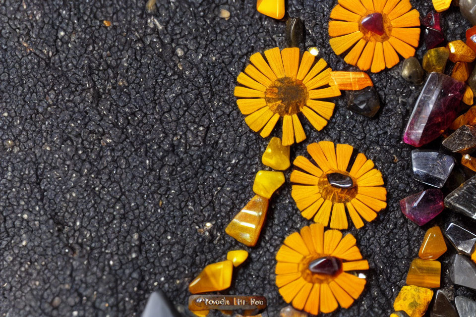 Orange Marigold Petals and Colorful Crystals on Black Surface