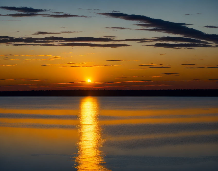 Tranquil sunset over calm lake with sun's reflection