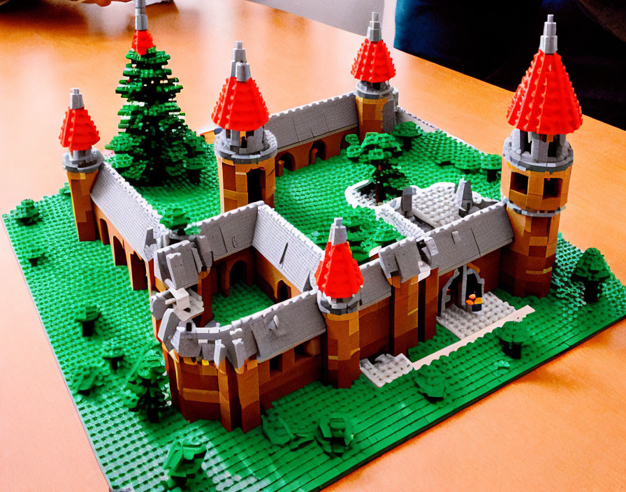 Detailed Lego castle with red rooftops and greenery on green base table display