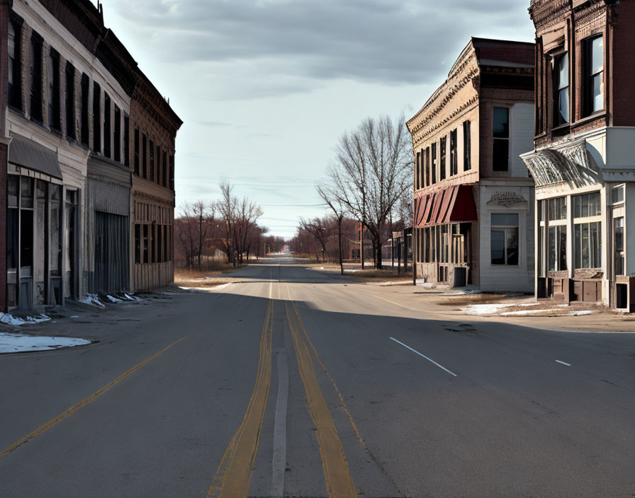 Deserted street between two-story buildings with snow patches.