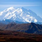 Snow-capped mountain and brown terrain under blue sky