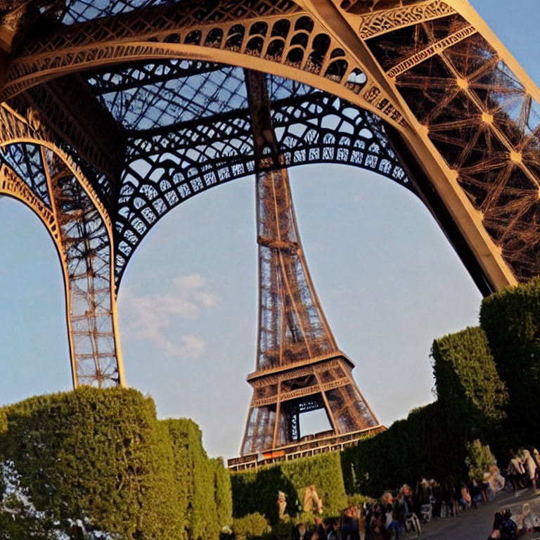 Eiffel Tower's intricate metalwork from below with visitors against dusky sky