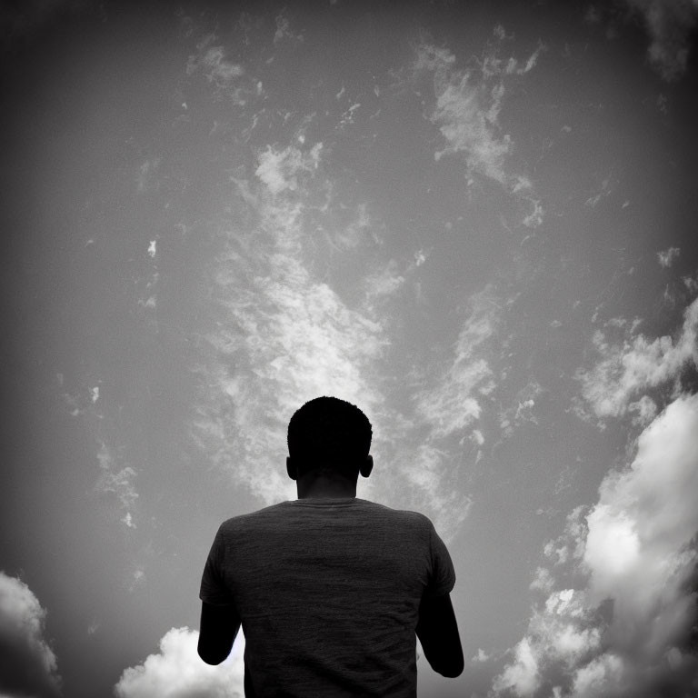 Monochrome photo of person gazing at dramatic cloudy sky