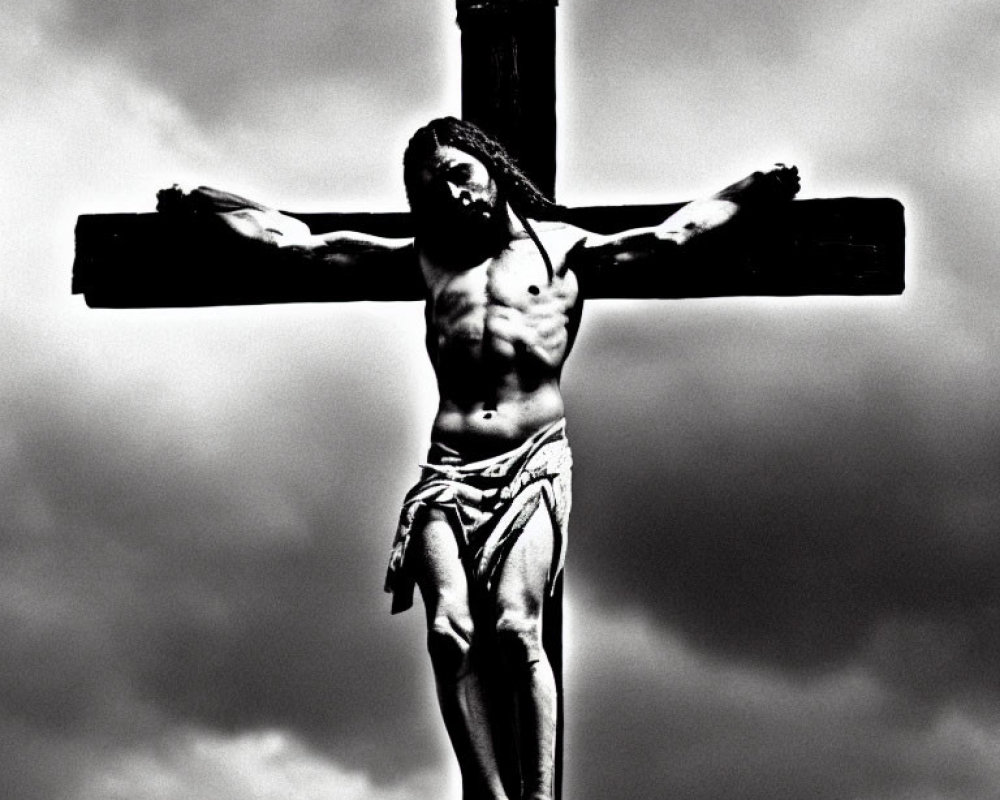 Monochrome sculpture of man on cross under cloudy sky