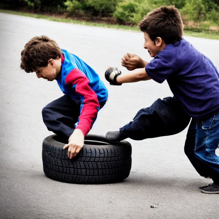 Boys playing with tire on paved surface