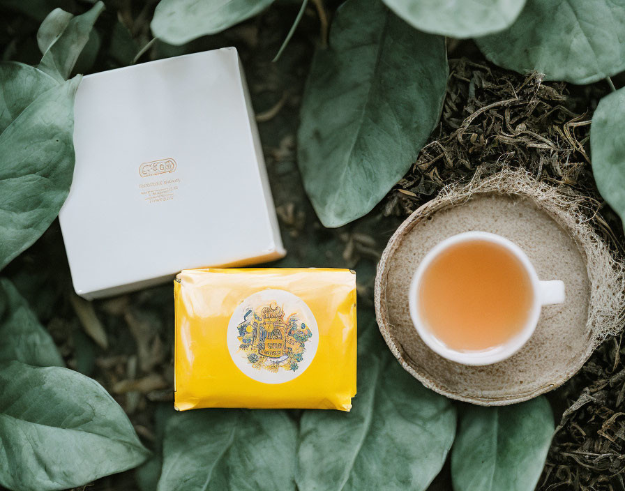 Yellow Packaged Tea with White Box Among Green Leaves