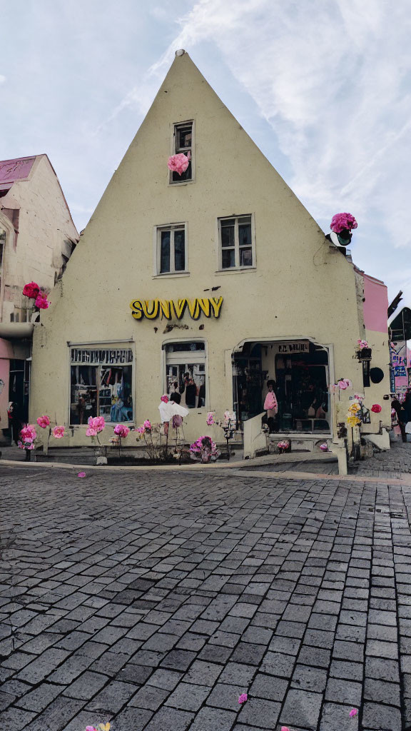 Triangular facade building with pink flowers and cobblestone street