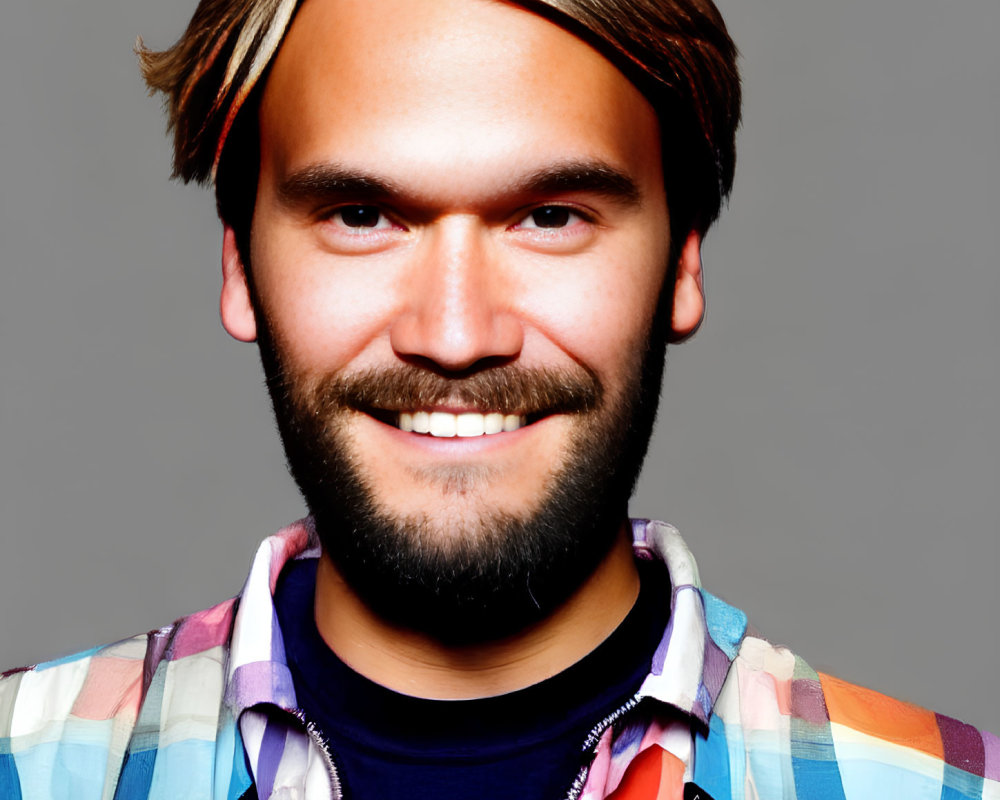 Bearded man with long blond hair in colorful checkered shirt on grey background