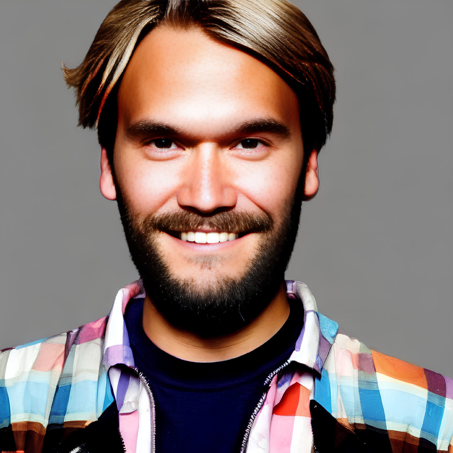 Bearded man with long blond hair in colorful checkered shirt on grey background