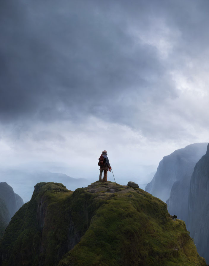 Hiker on green mountain peak under dramatic sky