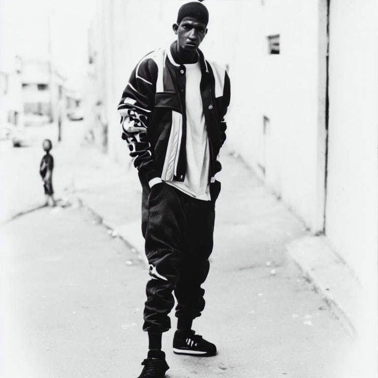 Confident man in varsity jacket in alley with child in background