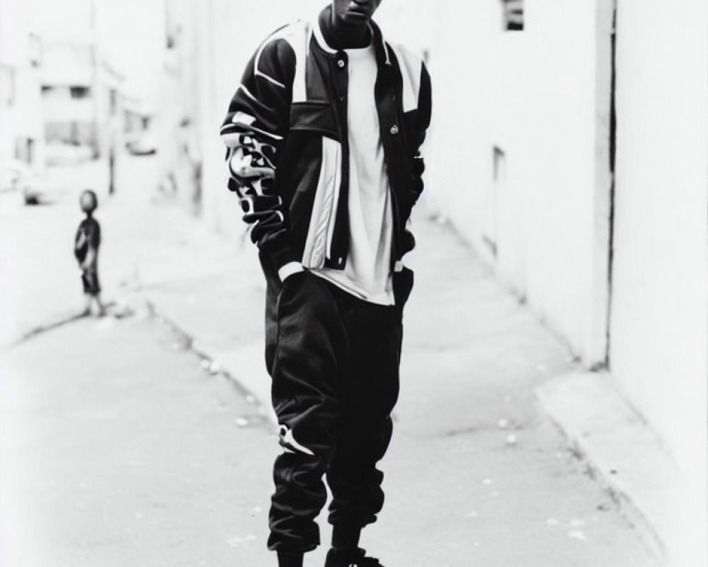 Confident man in varsity jacket in alley with child in background