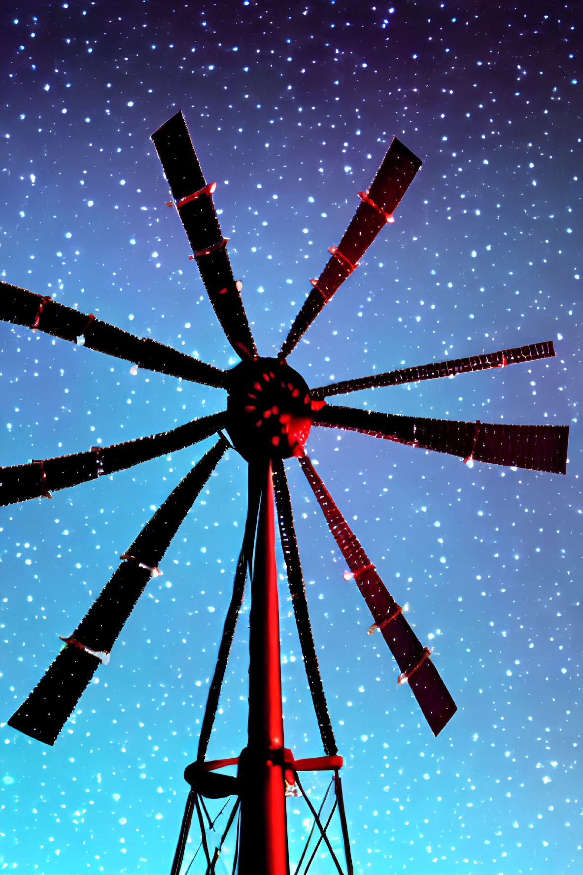 Silhouette of a windmill under starry night sky in blue gradient.