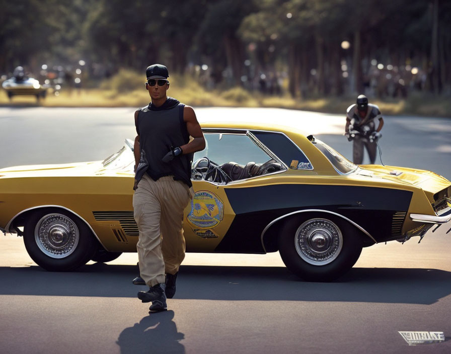 Man leaning on yellow vintage car with graphics, wearing sunglasses and black shirt, with passing car and motorcycle