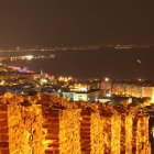 Cityscape at Night: Lit Streets Among Dense Buildings Near Calm Sea