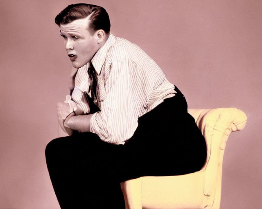 Slicked-back hair person in striped shirt on yellow chair against pink background