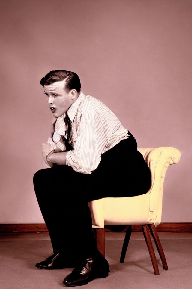 Slicked-back hair person in striped shirt on yellow chair against pink background